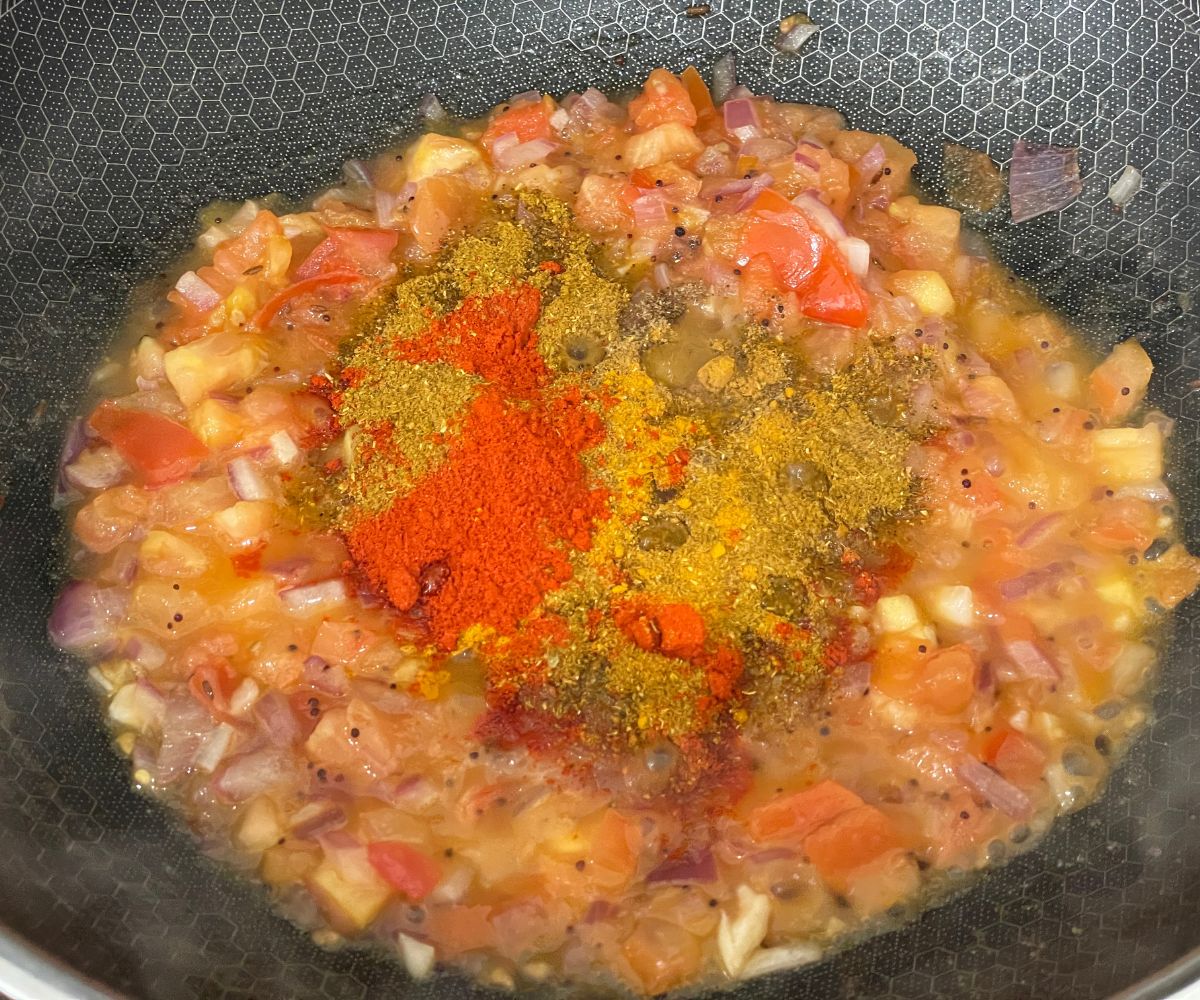 A pan has eggplant masala over the heat.