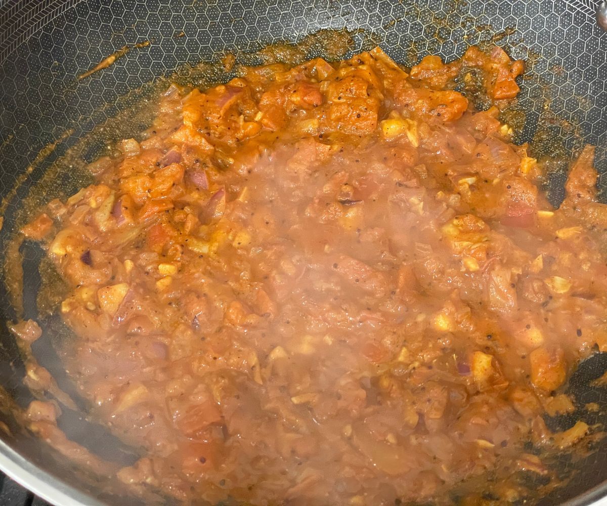 A heated pan has brinjal curry masala.