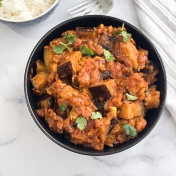 A bowl is full of Indian Eggplant masala curry.