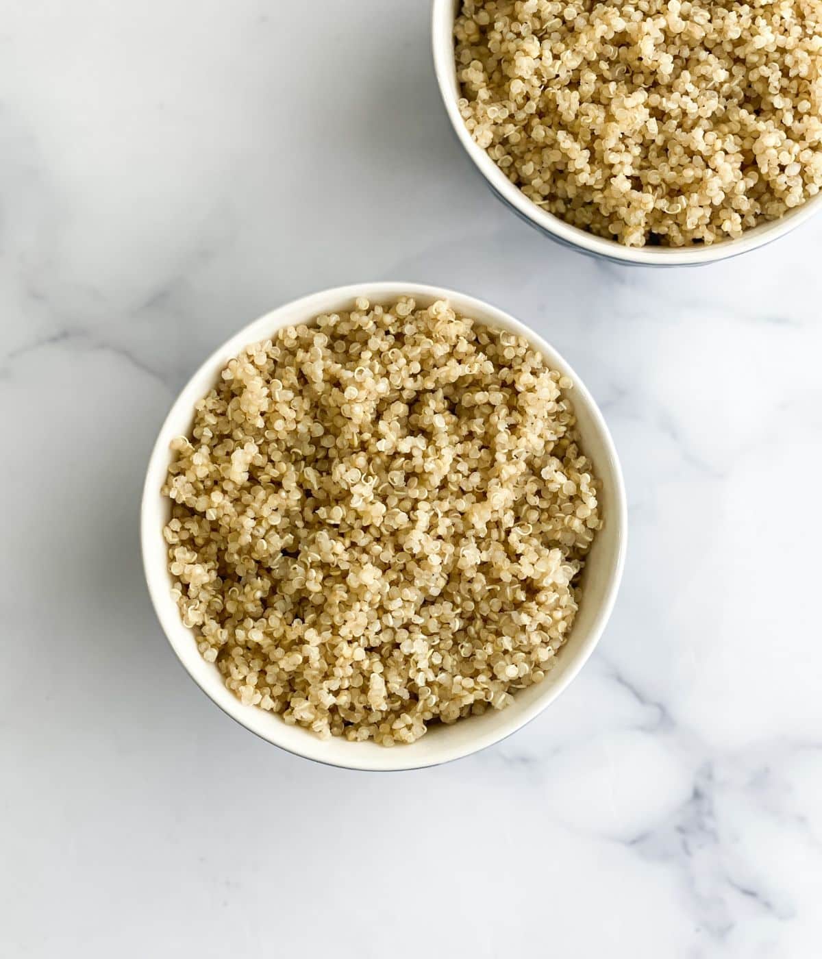 Two bowls have cooked quinoa. 