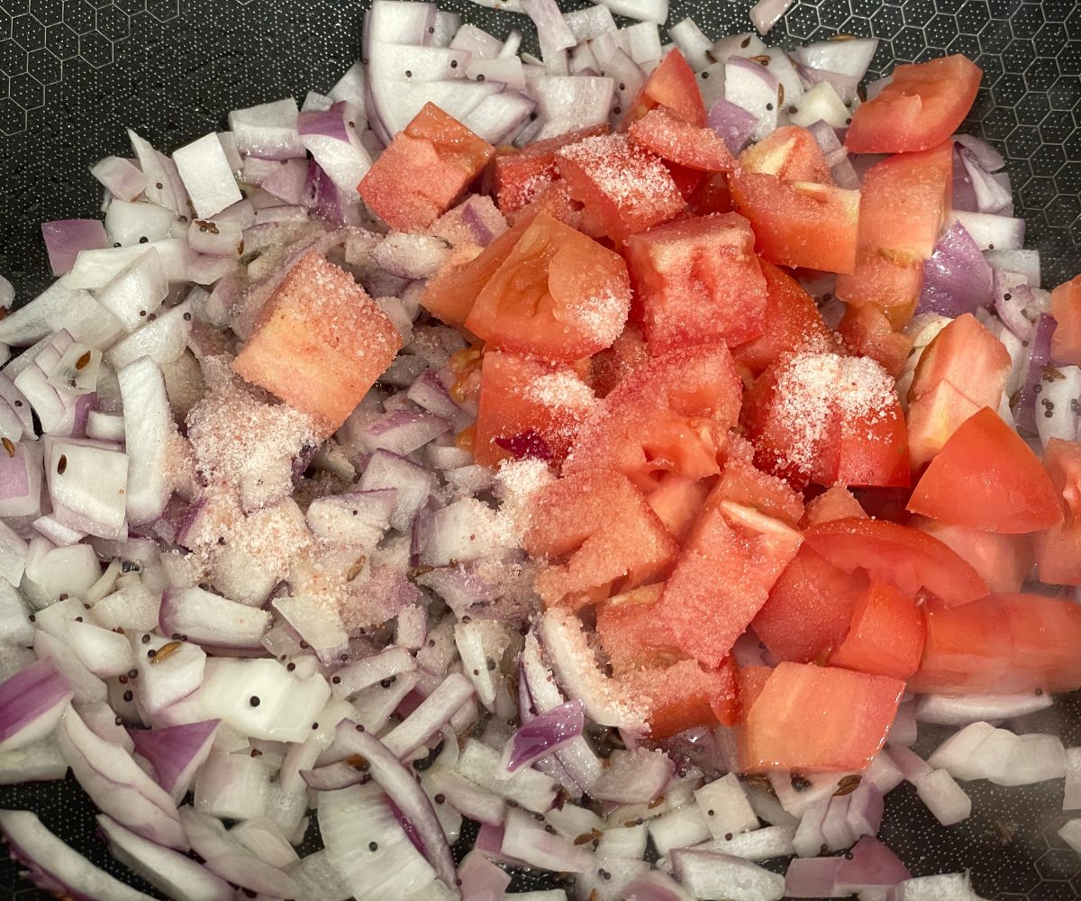 A pan has chopped onions and tomatoes.