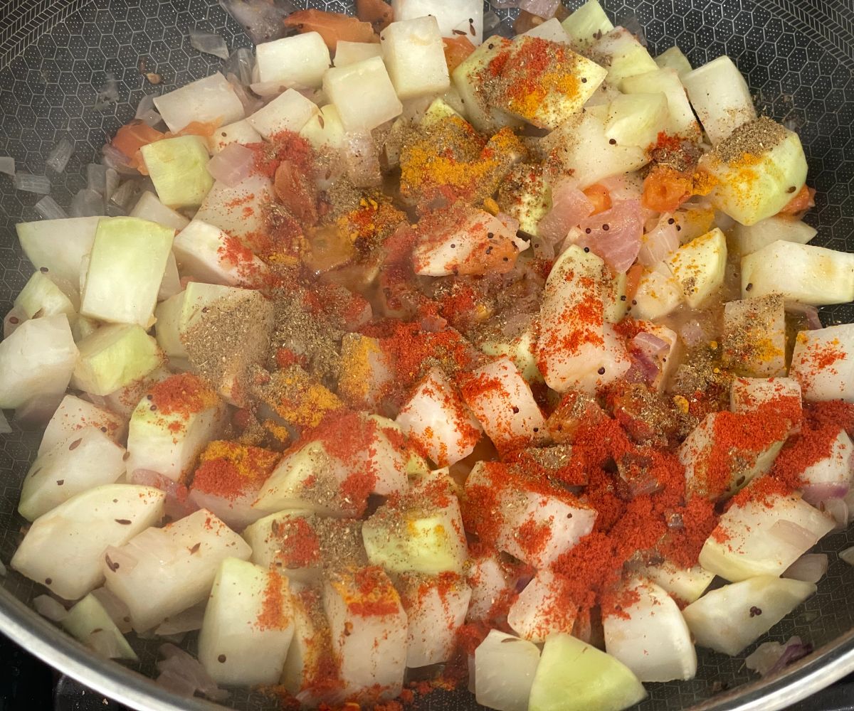 A pan has all the ingredients for kohlrabi curry.