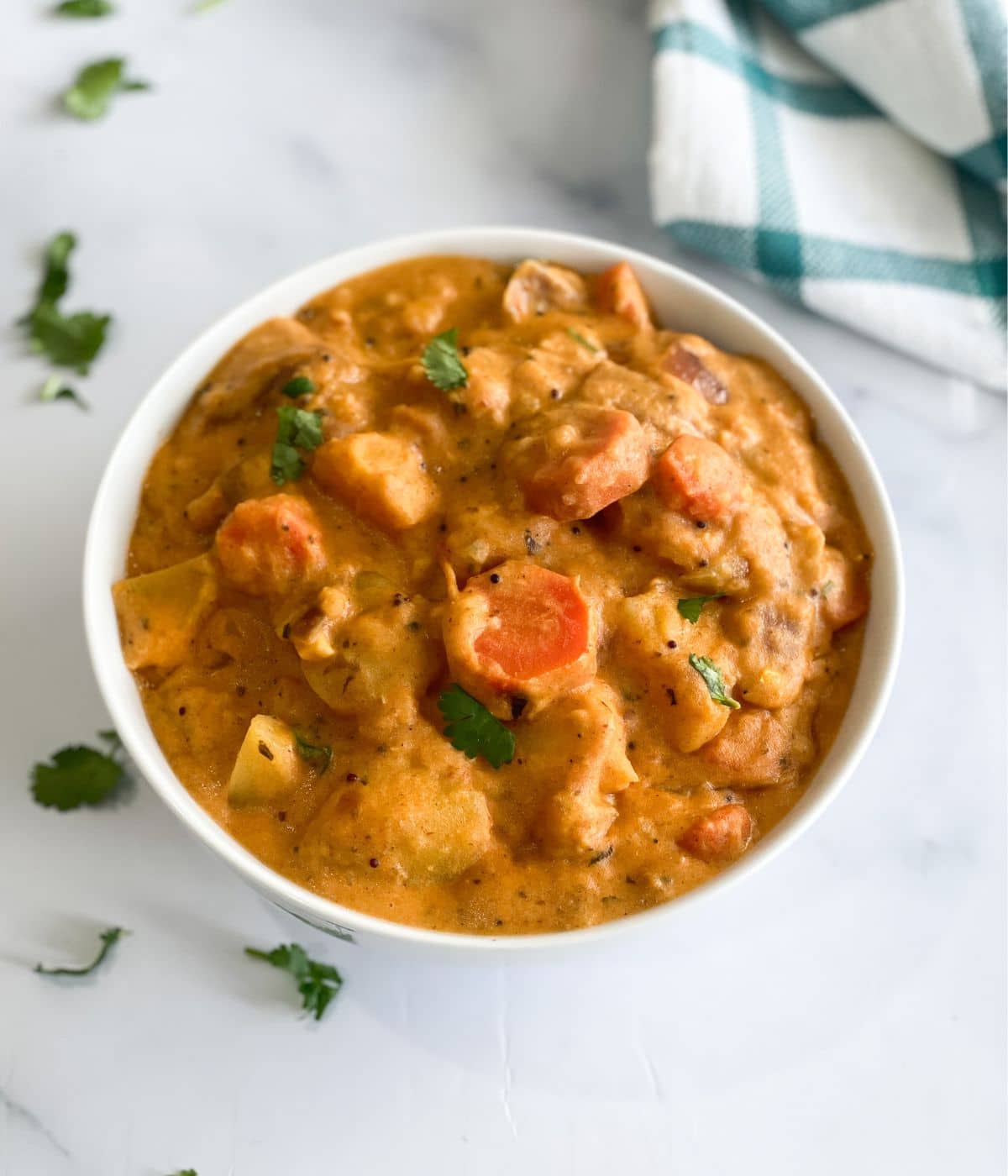 A bowl of vegan potato curry is on the table.