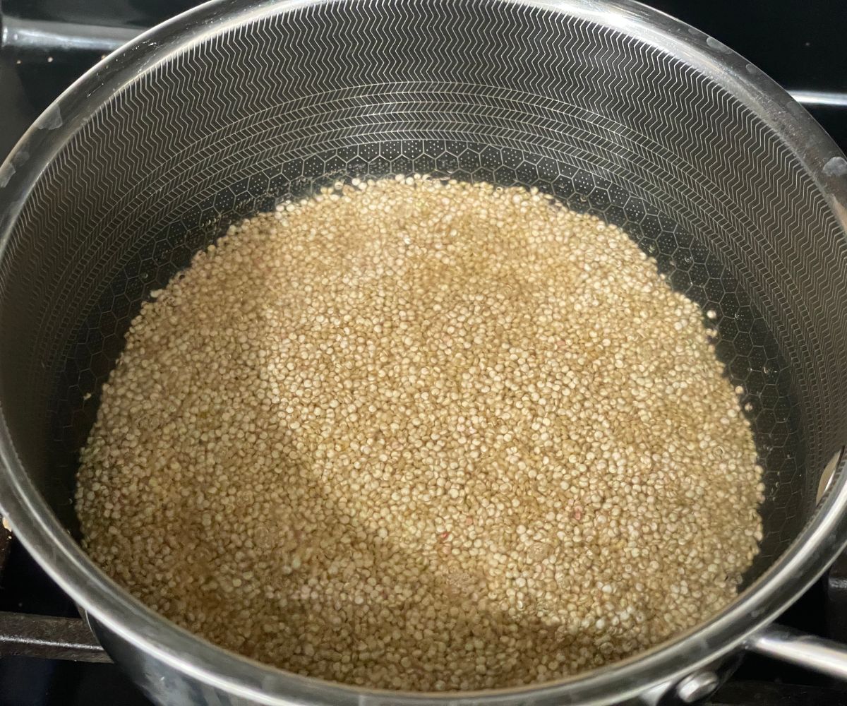 A pot of water and quinoa is on the stove top.