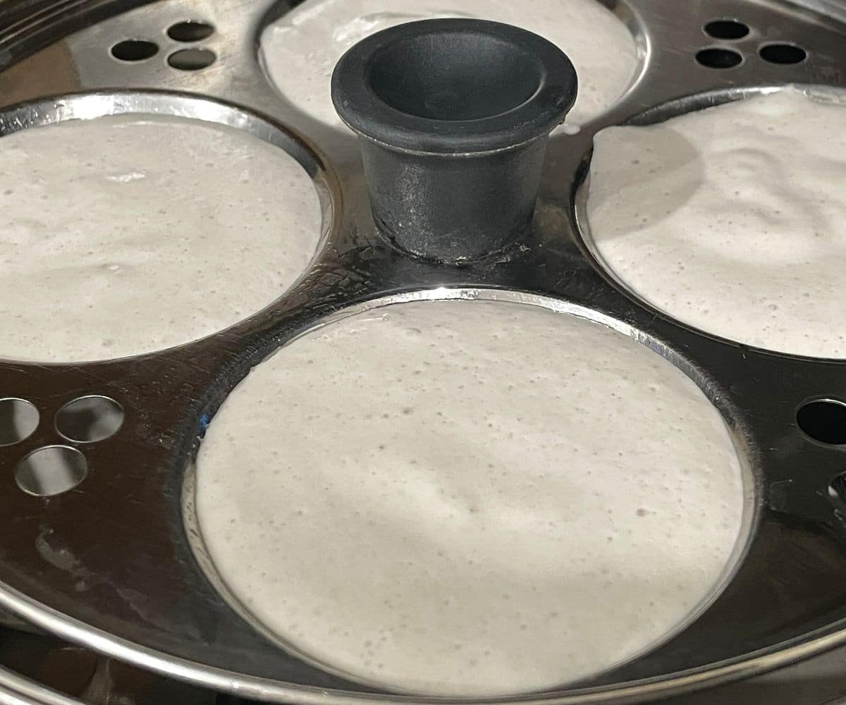 A idli stand is filled with quinoa idli batter.