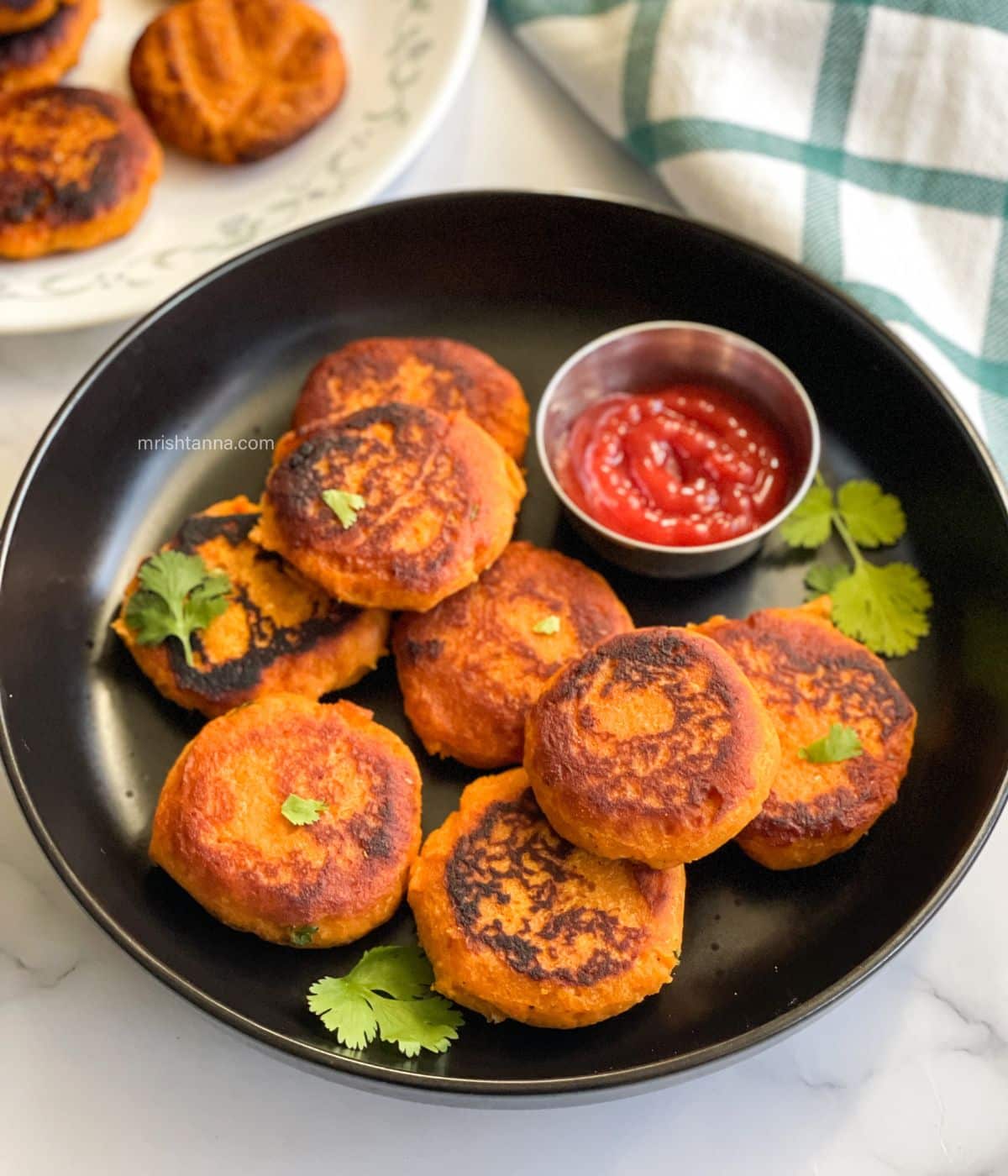 A plate is full of sweet potato cutlets and ketchup.