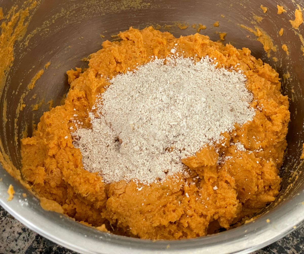 A bowl has mixed sweet potato tikki mixture inside.