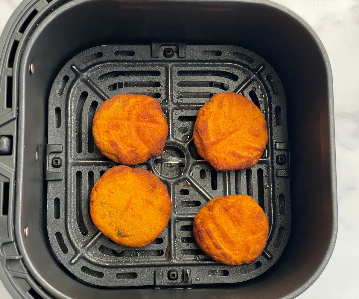 Air fryer basket has fried sweet potato cutlets.