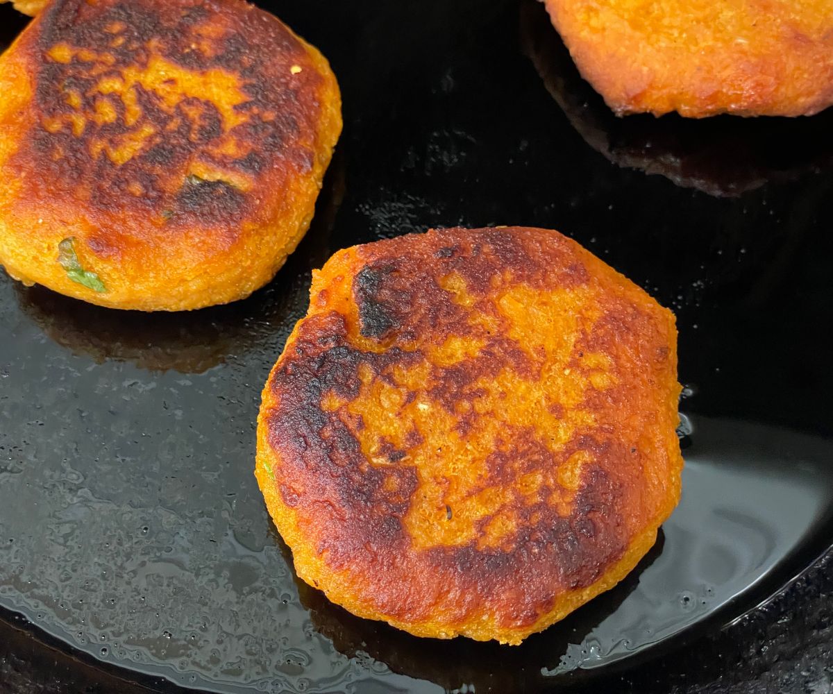 A pan has fried sweet potato tikki.