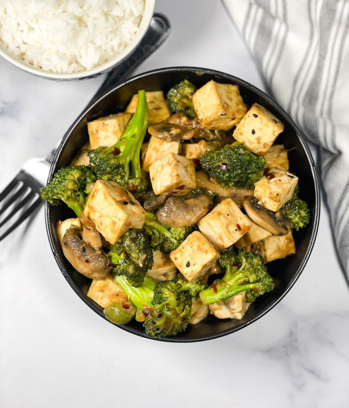 A bowl is full of tofu broccoli mushroom stir fry.