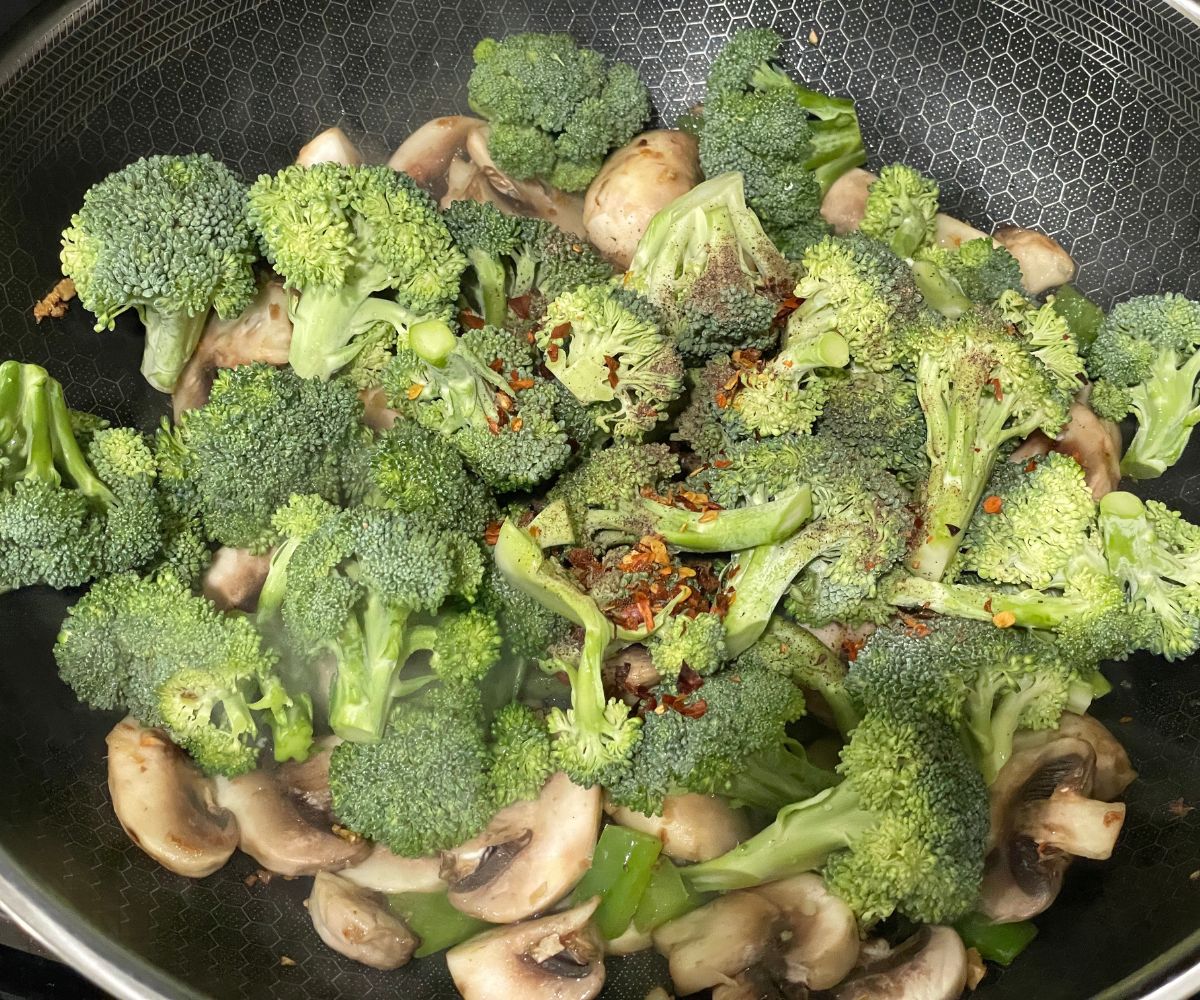 A wok has all the veggies on the stove top.