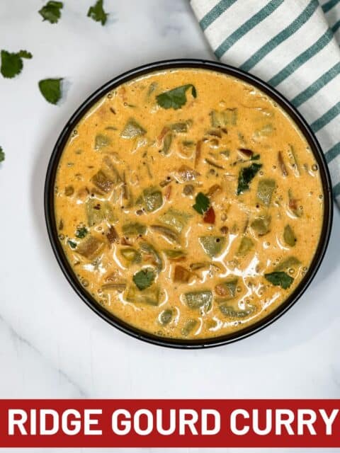 A bowl has ridge gourd curry on the table.