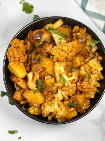 A bowl is full of cauliflower and potato curry.