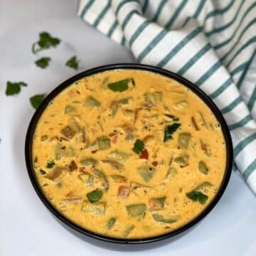 A bowl of ridge gourd curry is on the surface.