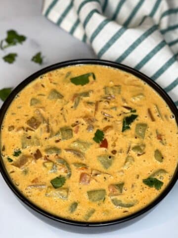 A bowl of ridge gourd curry is on the surface.