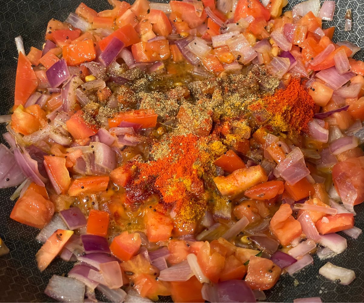 A pan has all the spices and tomatoes.