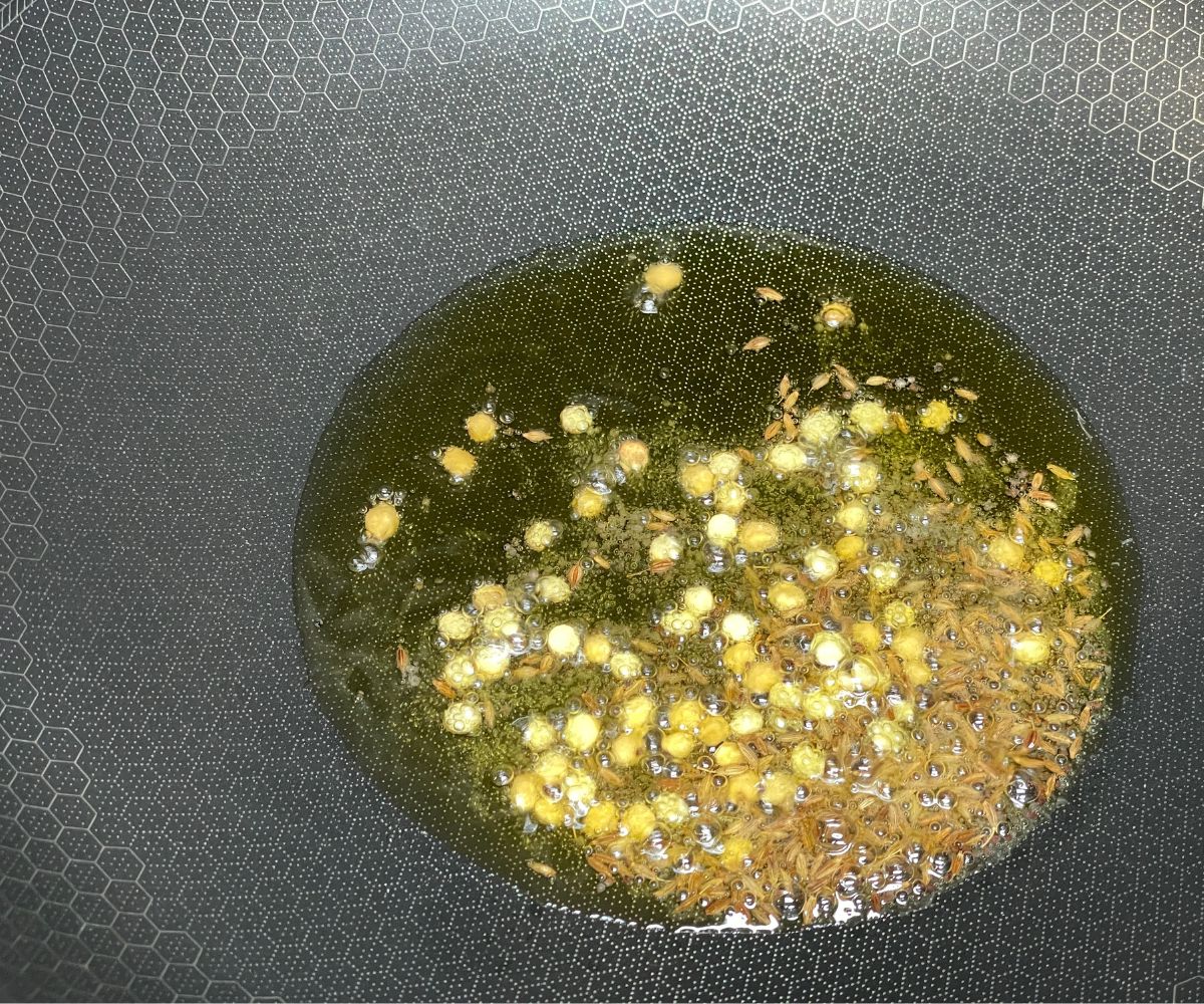 A pan is with oil  and whole spices over the heat.