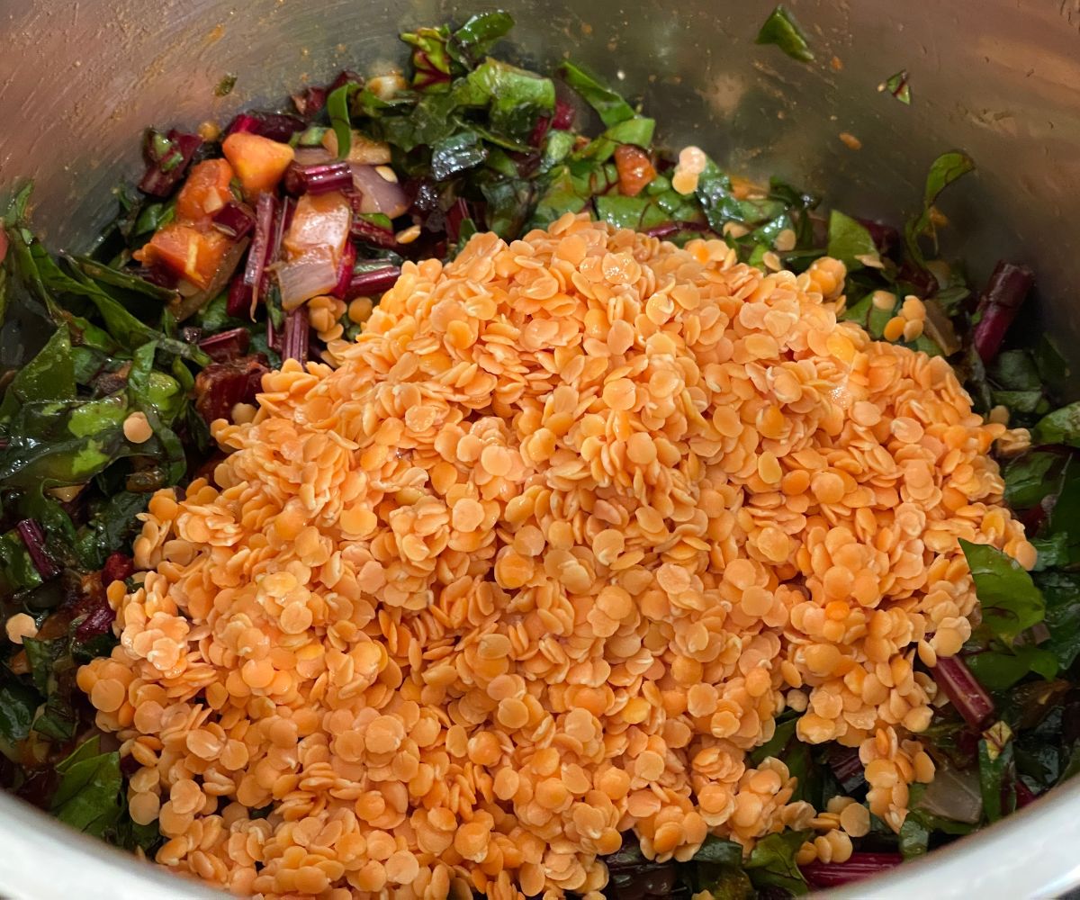 An instant pot has beet greens and masoor dal.