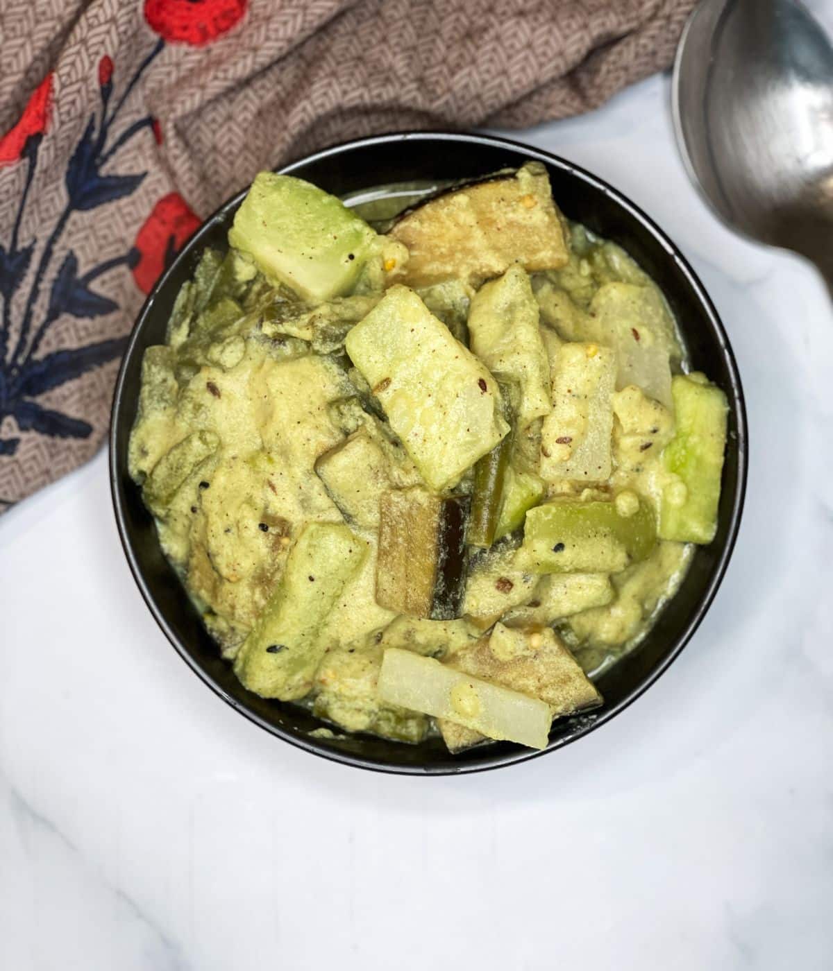 A bowl of Bengali mixed vegetable curry is on the surface.