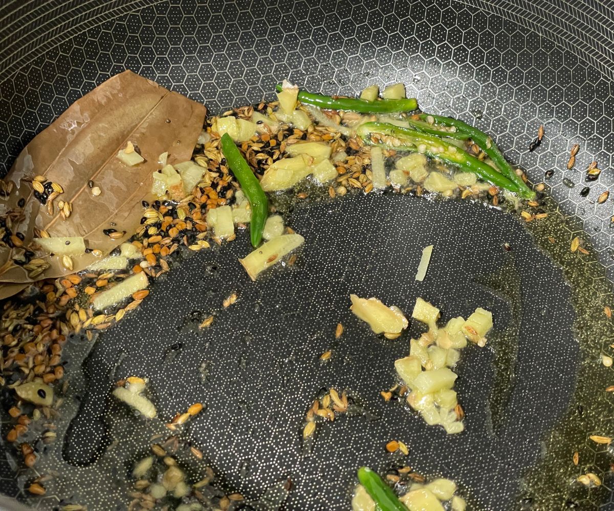 A pan has all the spices and green chilies over the heat.