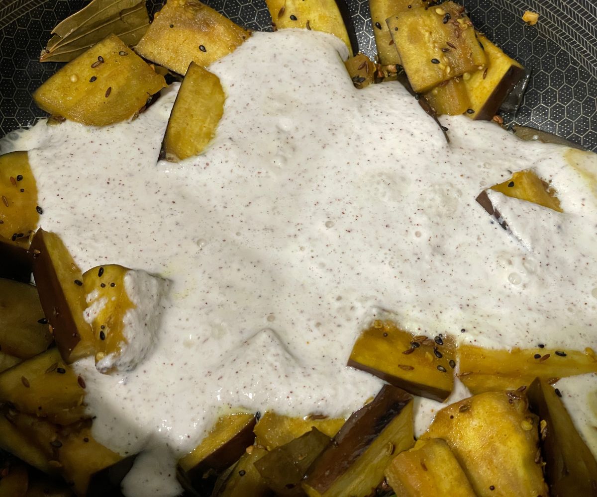 A pan has benagli shukto masala over the stove top.