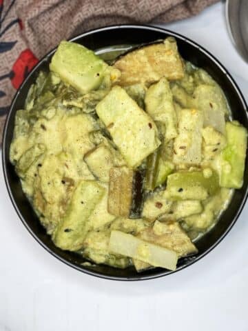 A bowl of Bengali shukto curry is on the table.