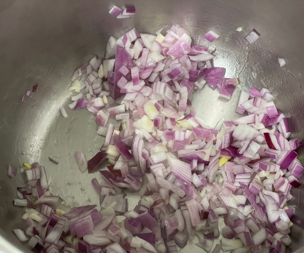 An instant pot has chopped  garlic and onions on saute mode.