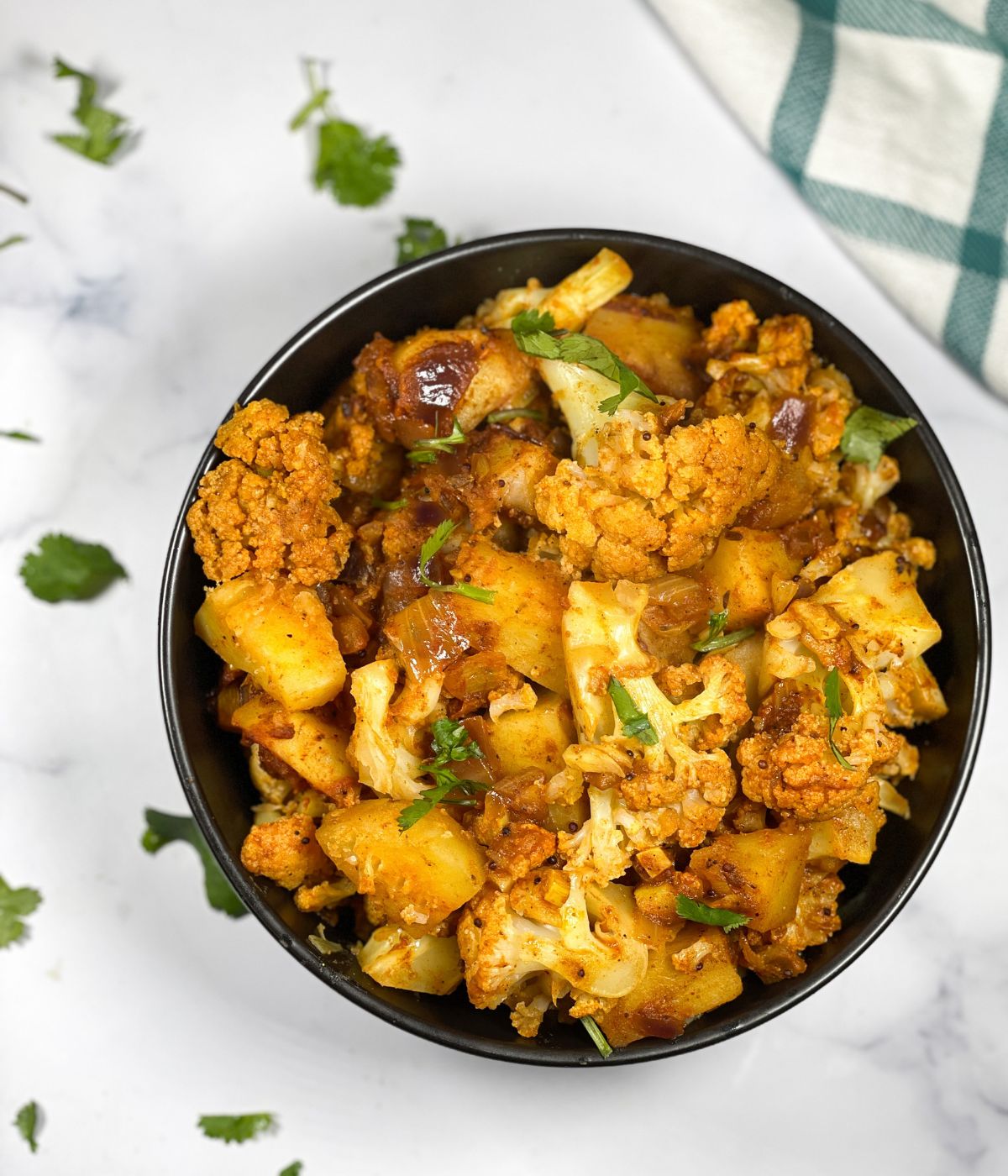 A bowl of aloo gobi is on the surface.