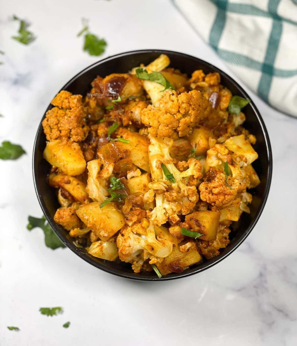 A bowl has instant pot aloo gobi curry.