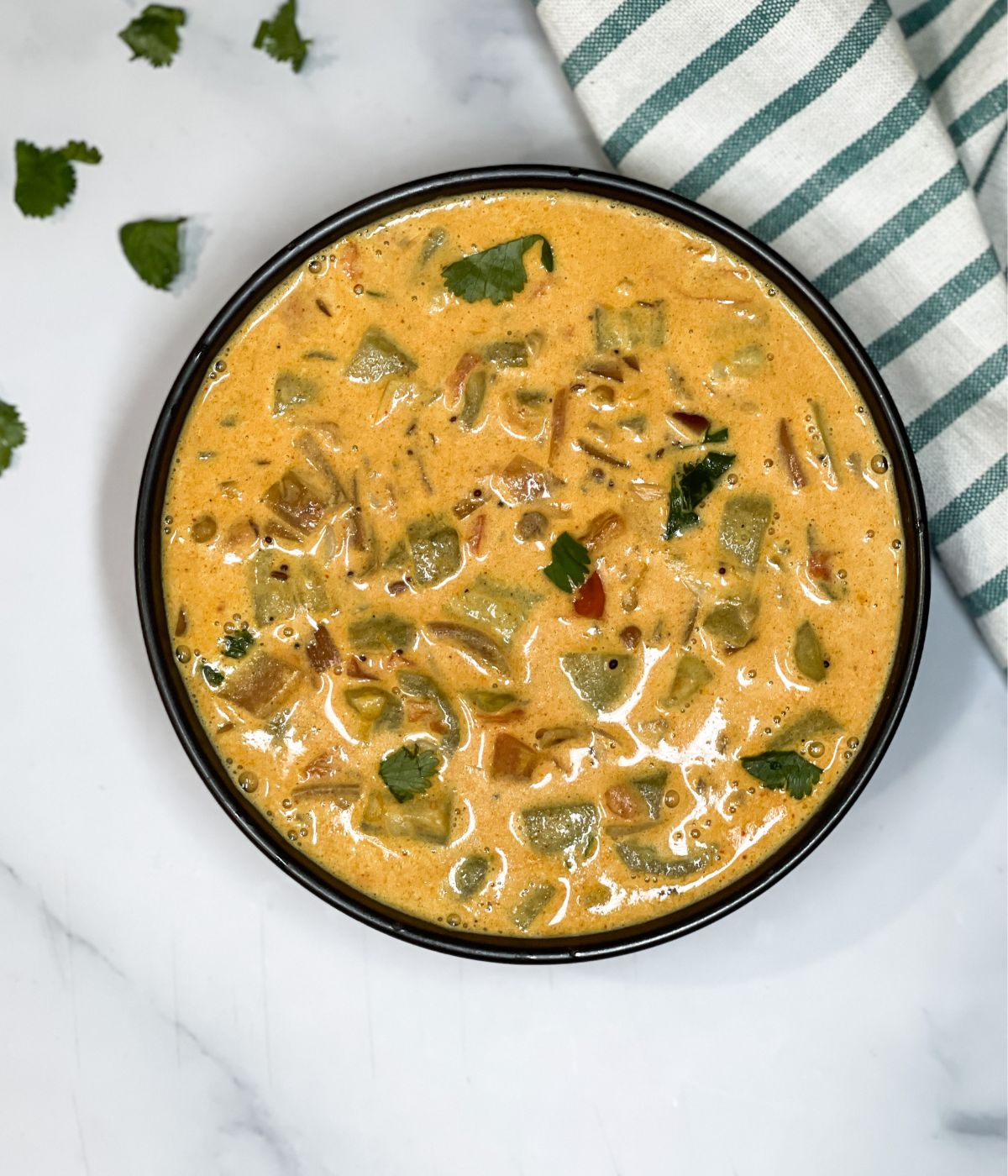 A bowl of ridge gourd curry is on the table.