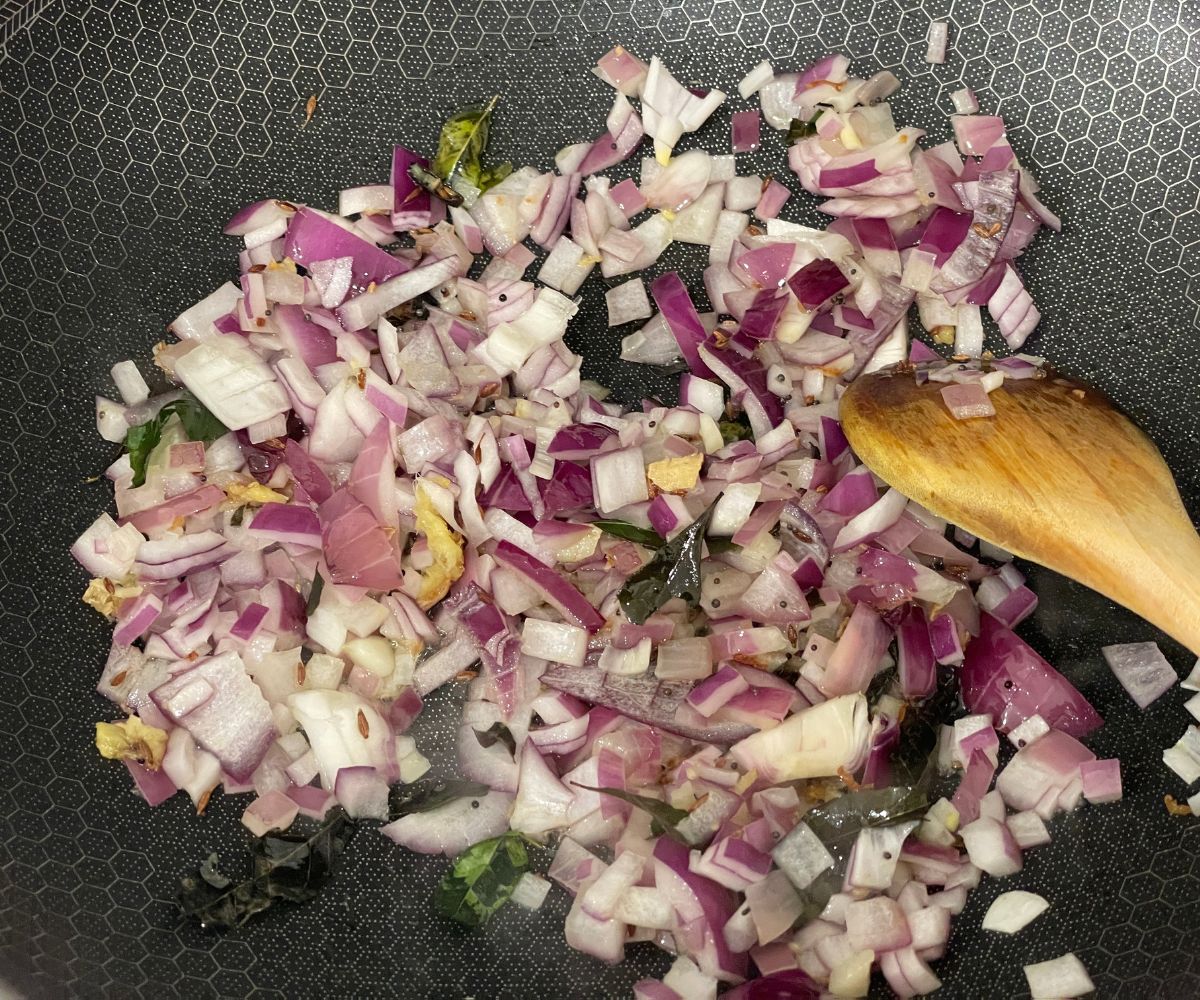 A pan has ginger and chopped onions over the heat.