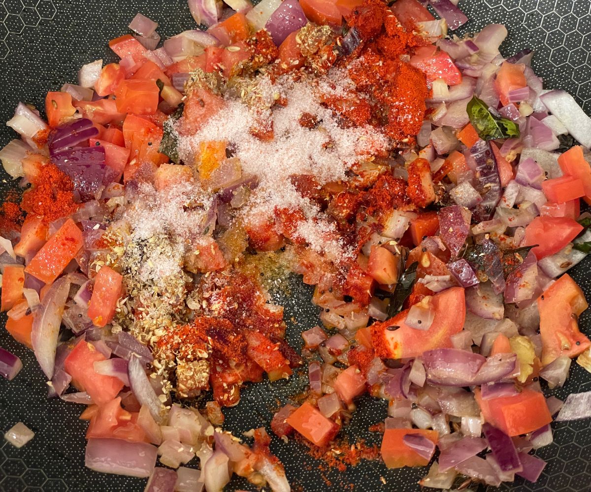 A pan has all the masalas for zucchini stir fry.