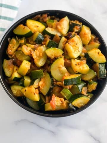 A bowl of zucchini sabzi is on the table.