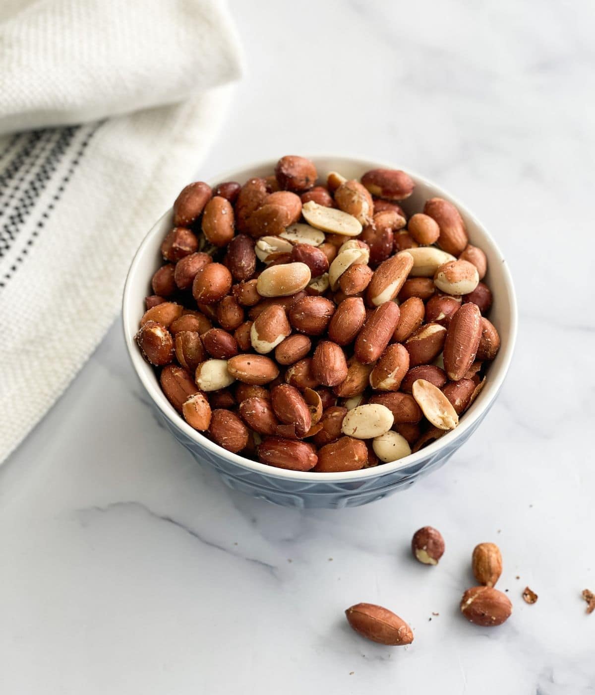A bowl of roasted peanuts are on the table.
