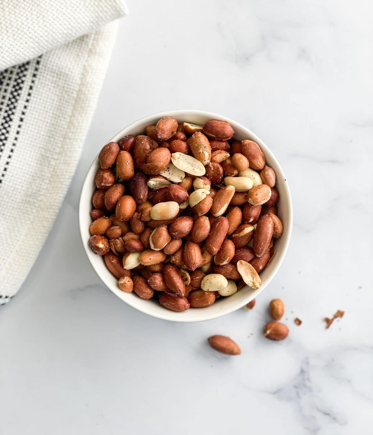 A bowl has air fried roasted peanuts on the table.