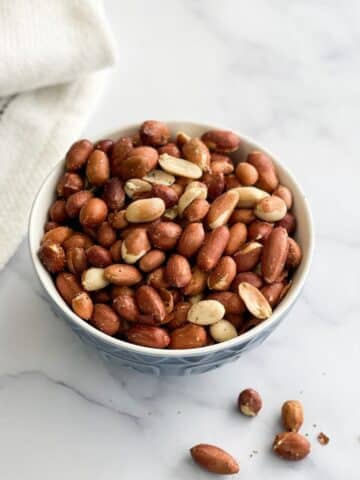 A bowl has roasted peanuts.