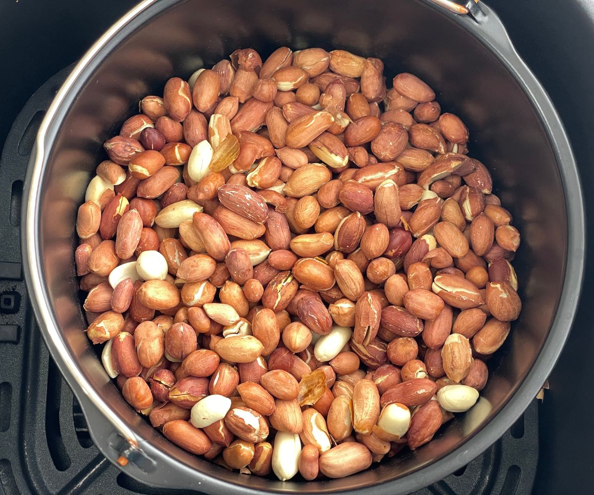 Air fryer basket is filled with roasted peanuts.