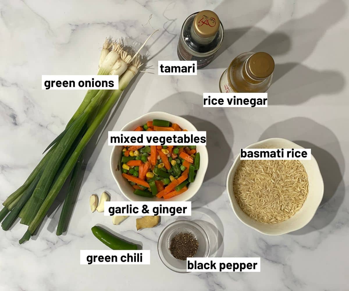 A table is filled with vegetable fried rice ingredients.