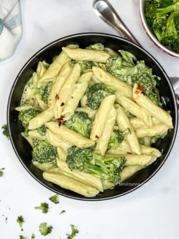 A bowl of broccoli pasta is on the surface.