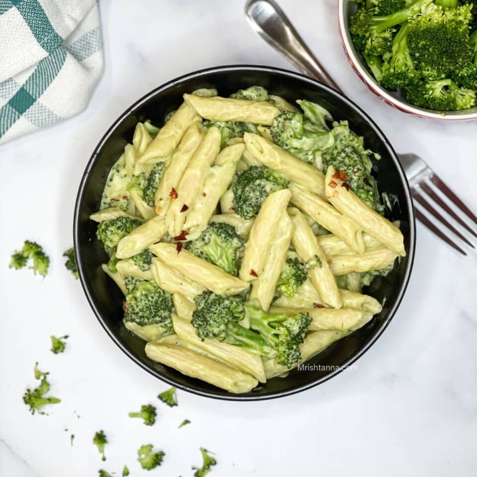 A bowl of broccoli pasta is on the surface.