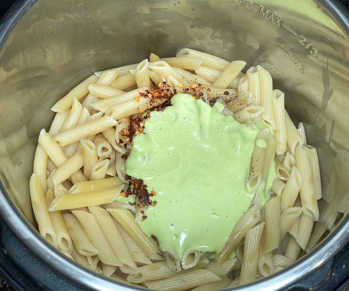 An Instant pot has cooked pasta, creamy sauce and chili flakes.