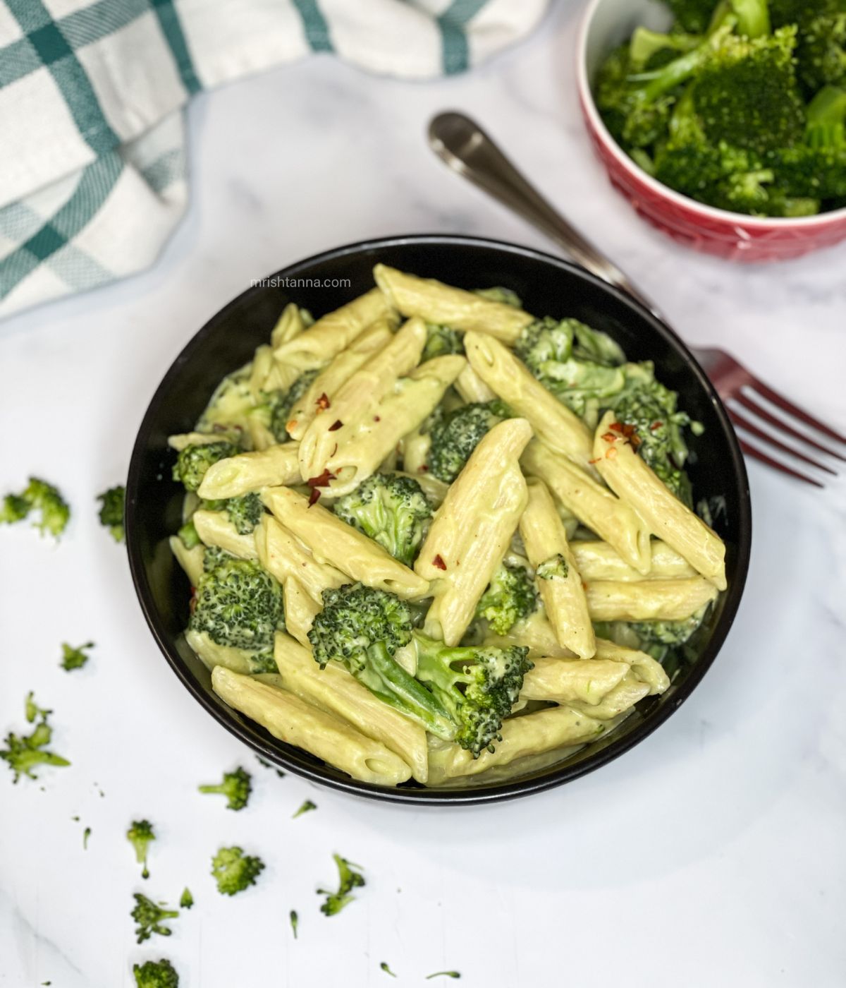 A bowl of broccoli pasta is on the table.