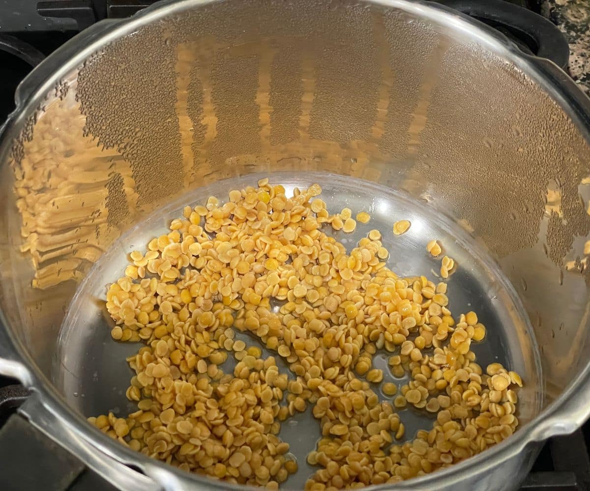 A pressure cooker is having rinsed toor Dal.