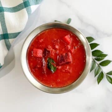 A bowl of Kerala style Sambar is on the white surface.