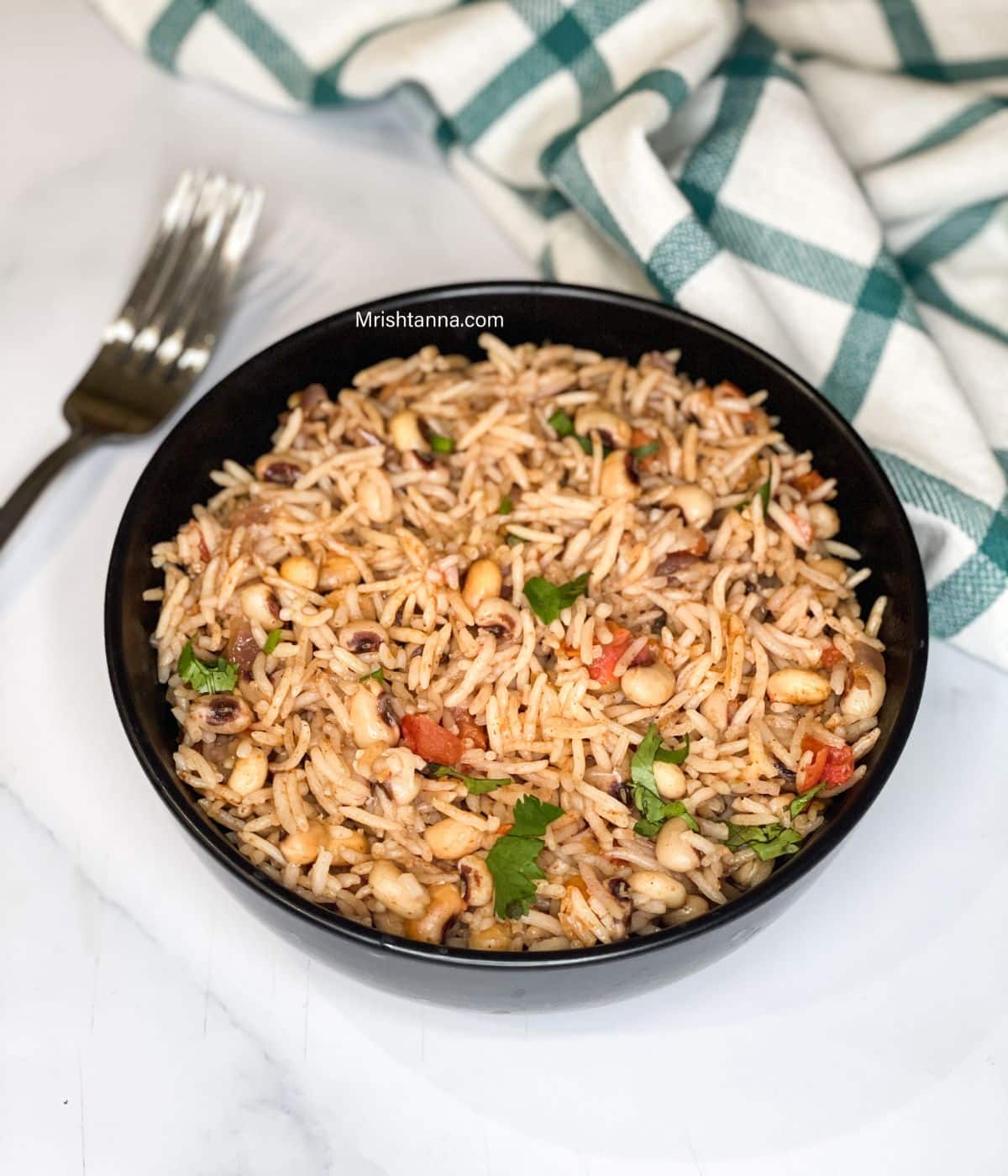 A bowl of black eyed peas pulao is on the surface.