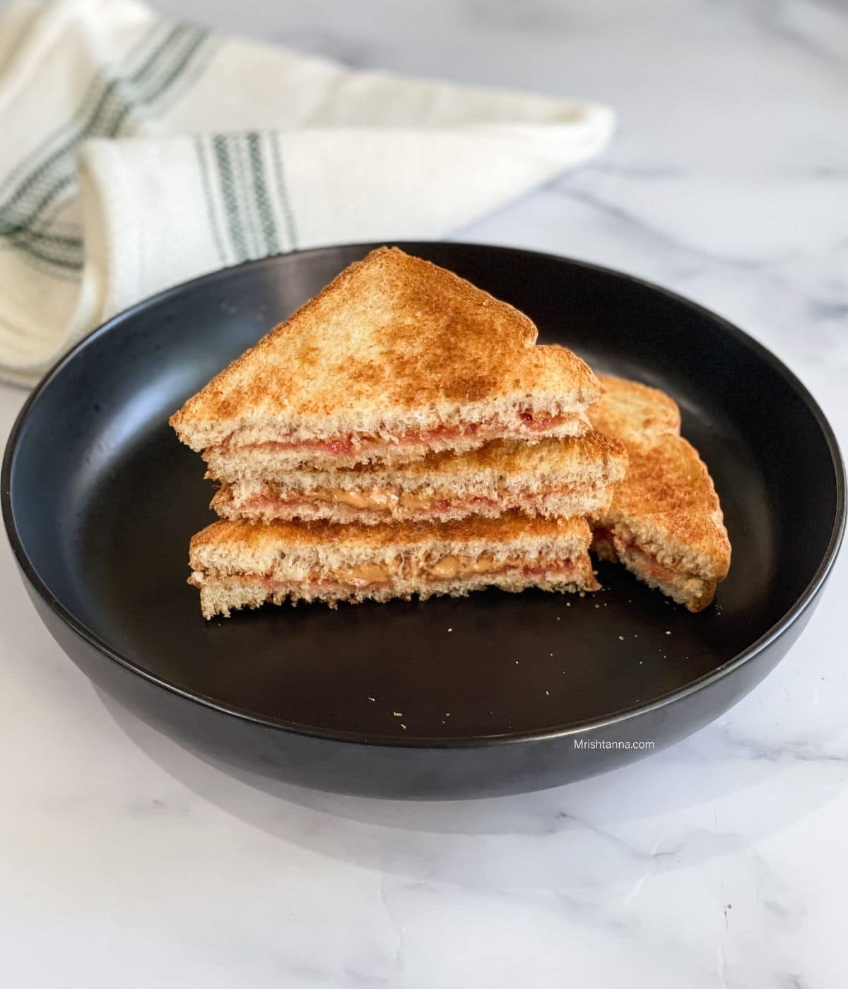 A plate of peanut butter jelly sandwich is on the table.