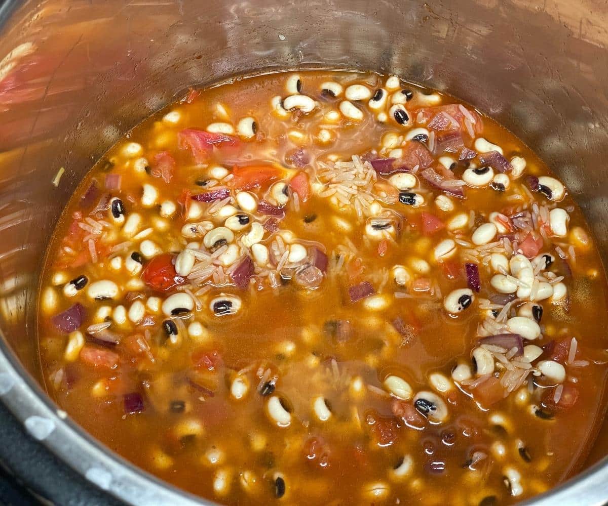 An instant pot has black eyed peas rice ingredients on cooking mode.