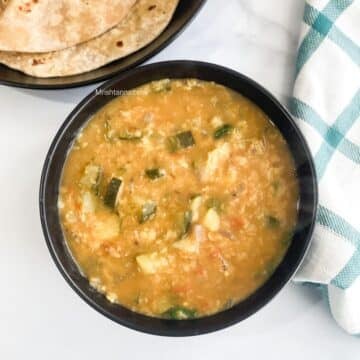A bowl of zucchini dal is on the surface.