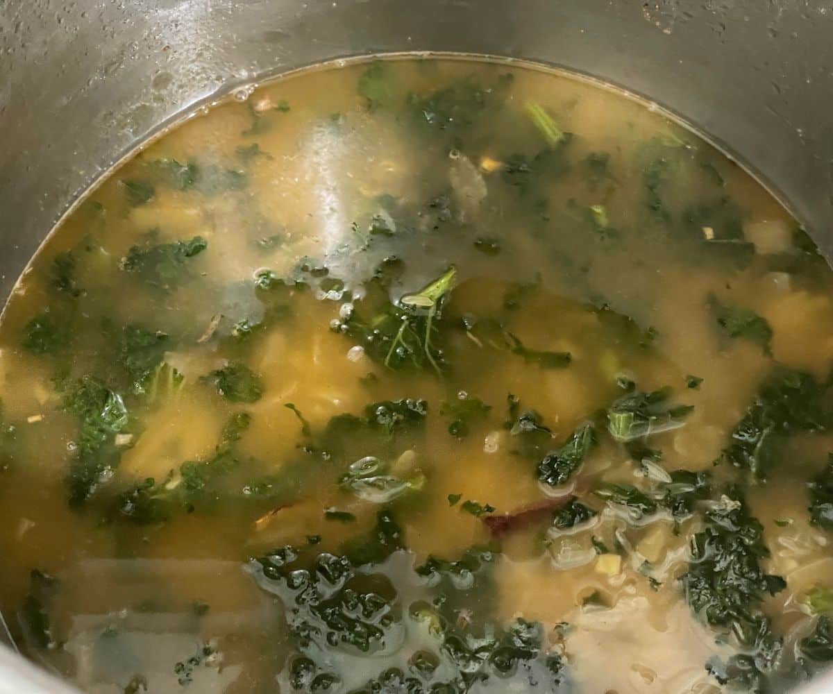 A pot has all the kale rice ingredients to make.