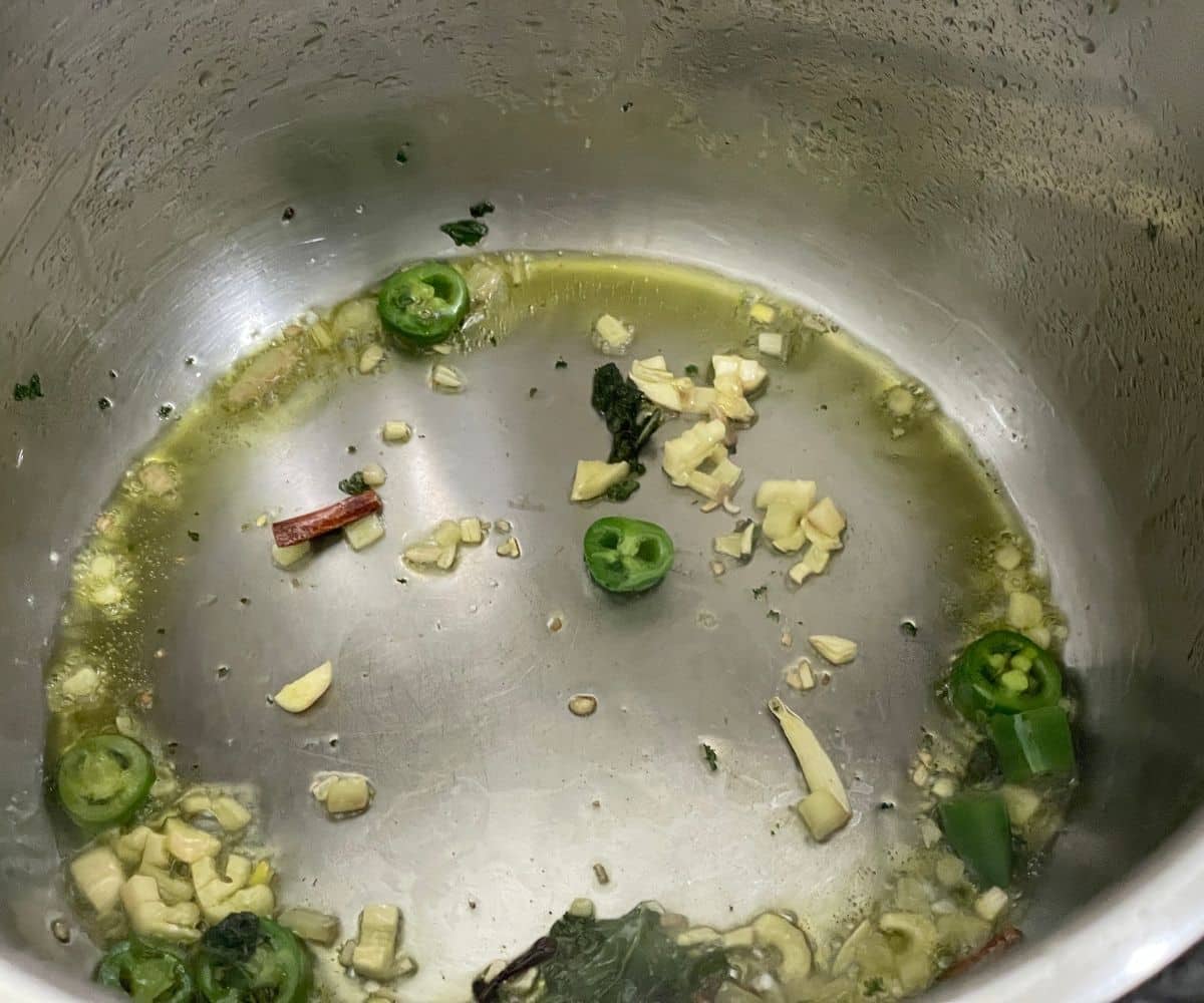 An instant pot has ginger, garlic and chilies in a saute mode.